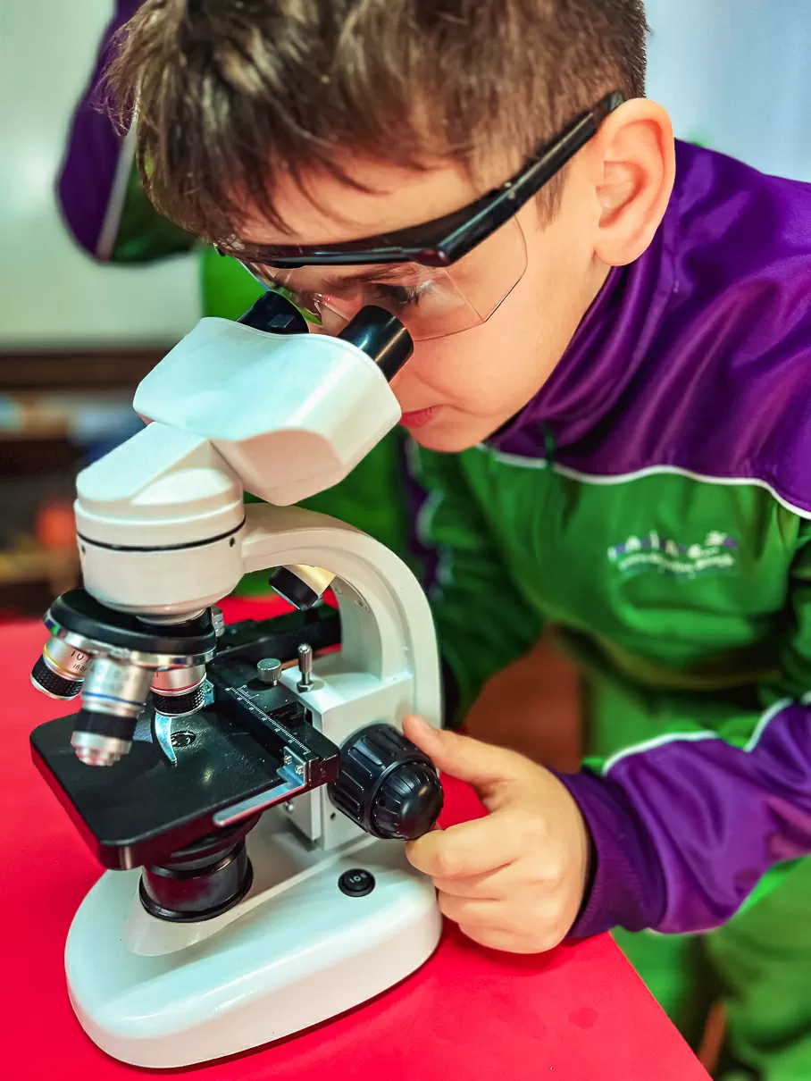 Niño en laboratorio con un microscopio